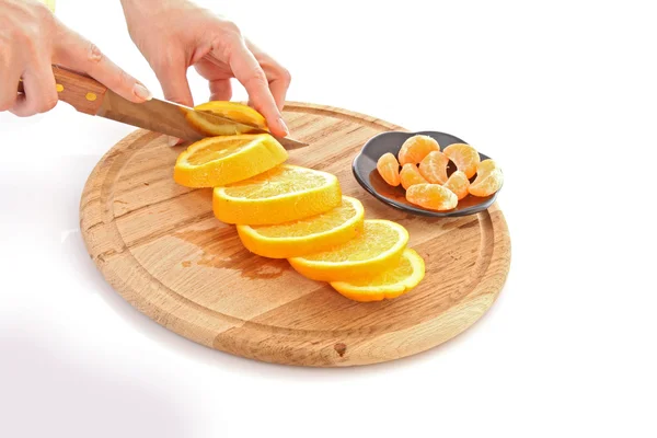 Руки вырезают апельсины на столе — стоковое фото