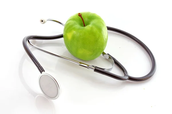 Stethoskop und grüner Apfel auf weißem Hintergrund — Stockfoto