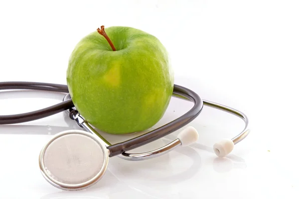 Стетоскоп и зеленое яблоко на белом фоне — стоковое фото