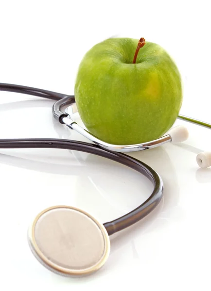 Estetoscópio e maçã verde no fundo branco — Fotografia de Stock