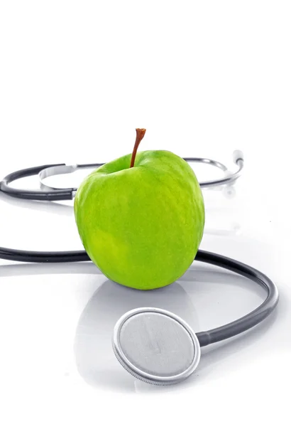 Estetoscópio e maçã verde no fundo branco — Fotografia de Stock