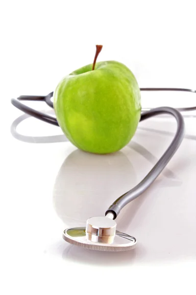 Stetoskop a zelené jablko na bílém pozadí — Stock fotografie
