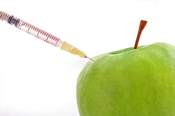 Зеленое яблоко со шприцем на белом фоне — стоковое фото