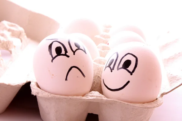 Due uova con facce su bianco — Foto Stock