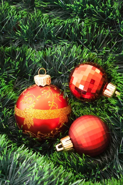 Red Christmas balls and presents among green new year tree — Stock Photo, Image
