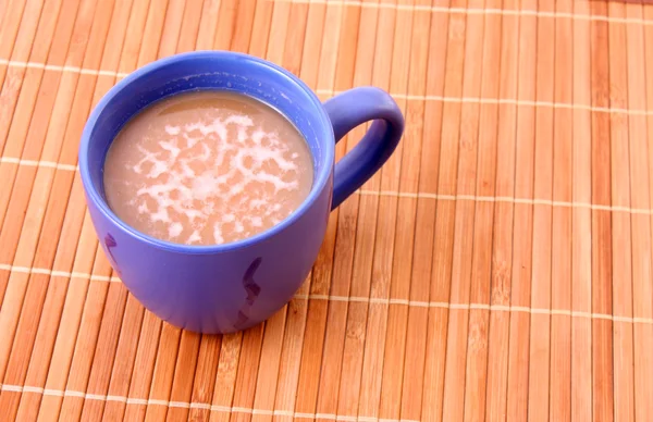 Café con taza de color leche sobre fondo de paja de bambú — Foto de Stock