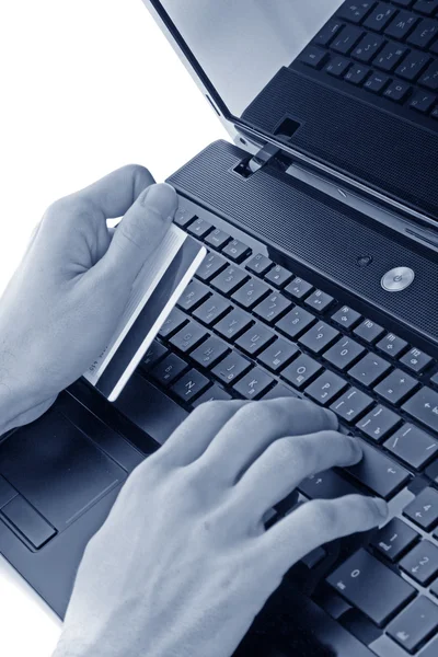 Closeup of men's hands holding credit cart by a laptop keyboard — Stock Photo, Image