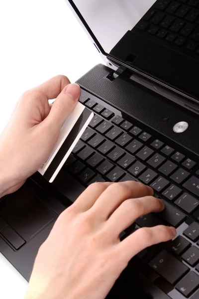 Primer plano de las manos de los hombres sosteniendo el carro de crédito por un teclado portátil — Foto de Stock
