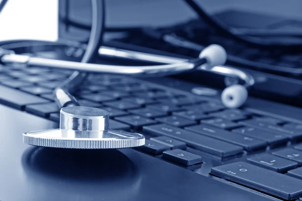 Doctor stethoscope on the laptop keyboard, image in blue tone — Stock Photo, Image