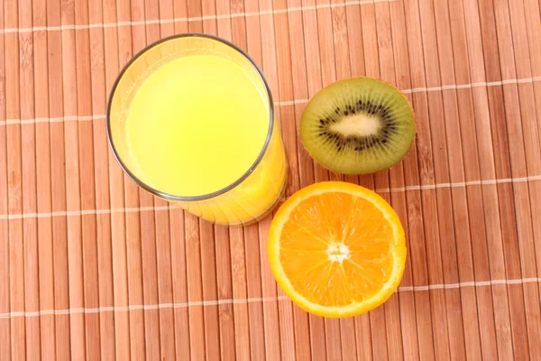 Orangen, Kiwi und Saft auf braunem Hintergrund — Stockfoto