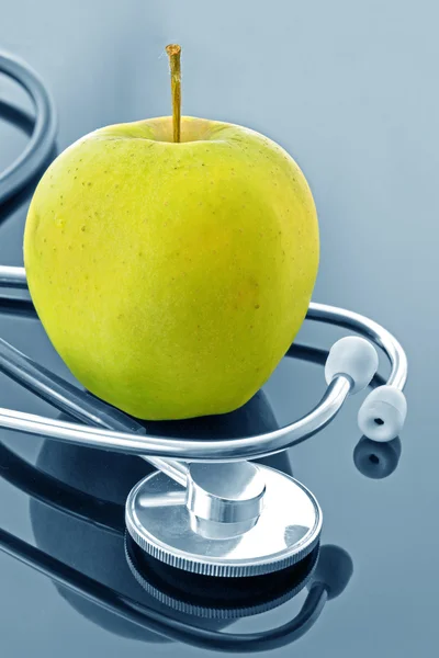 Фонендоскоп и яблоко на тёмном фоне — стоковое фото