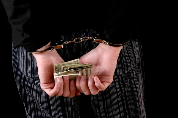 Чоловік з наручниками і доларами на чорному — стокове фото