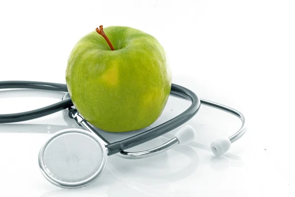 Stetoskop och grönt äpple på vit bakgrund Stockfoto