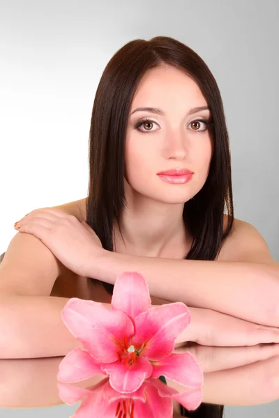Mulher bonita com flor de lírio no fundo cinza com m — Fotografia de Stock