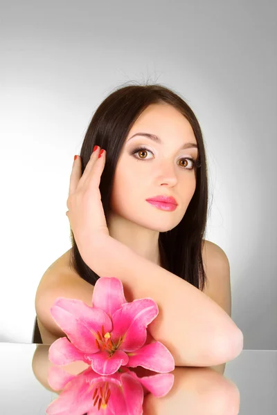 Beautiful young woman with lily flower on grey background with m — Stock Photo, Image