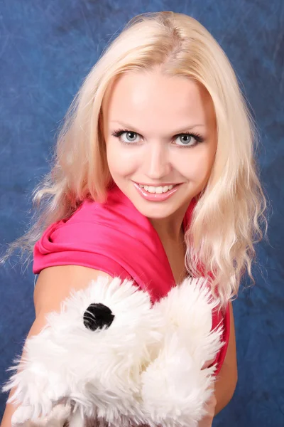 Krásná blondýnka v růžových šatech s malým psem na modré — Stock fotografie