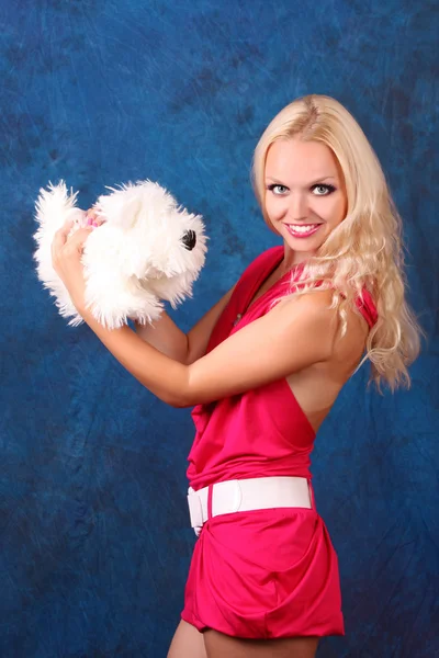 Beautiful blond girl in pink dress with small dog on blue — Stock Photo, Image