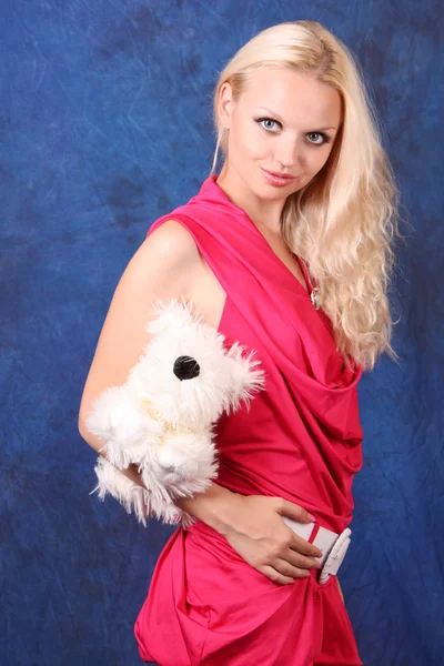 Beautiful blond girl in pink dress with small dog on blue — Stock Photo, Image