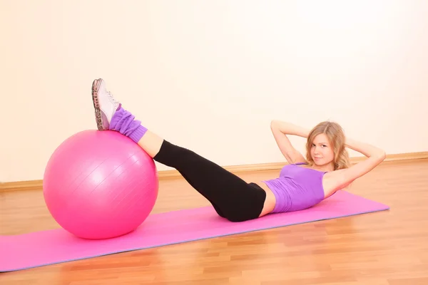 Jovem menina fitness bonita com bola rosa exercendo no g — Fotografia de Stock
