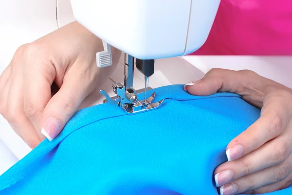 Máquina de costura, tecido azul e mãos das mulheres — Fotografia de Stock