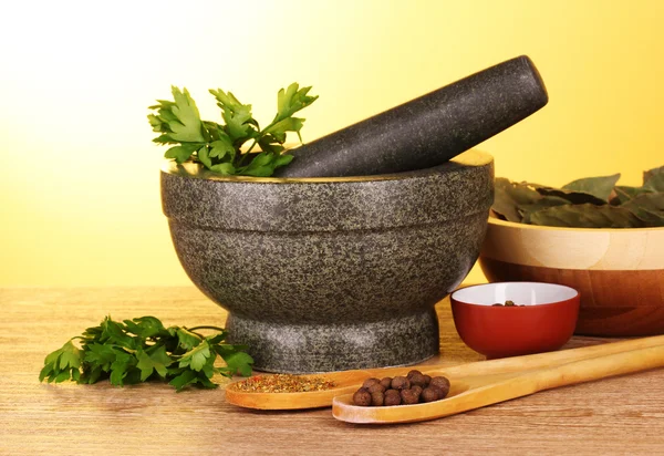 Mortar and pestle, bowls, parsley and pepper on yellow backgroun — Stock Photo, Image
