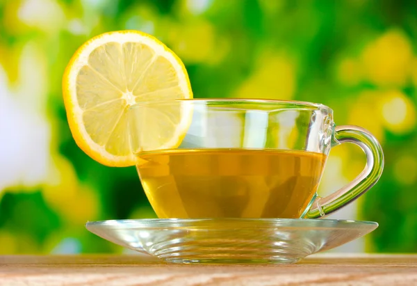 Чай с лимоном на фоне зеленых листьев — стоковое фото