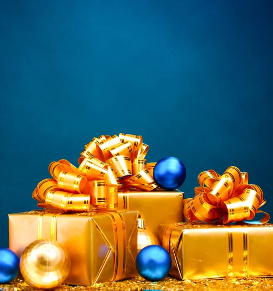 Belos presentes em embalagens de ouro e bolas de Natal em azul ba — Fotografia de Stock