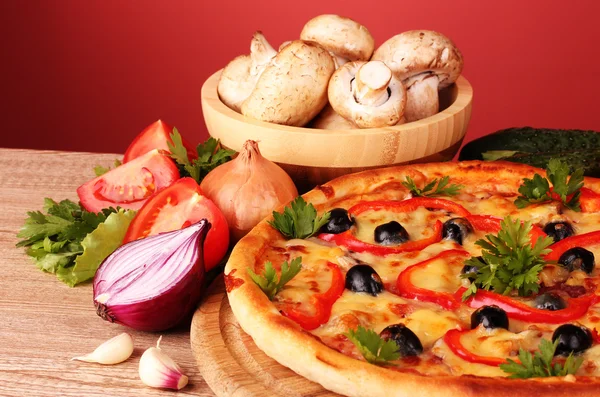 Pizza en groenten op rode achtergrond — Stockfoto