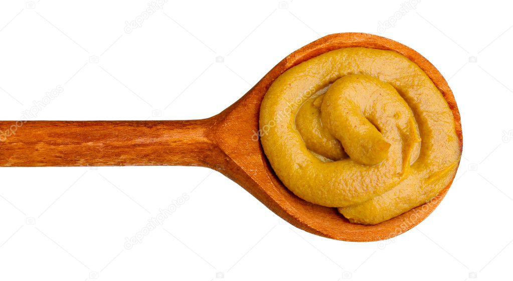 Mustard in a wooden spoon isolated on white