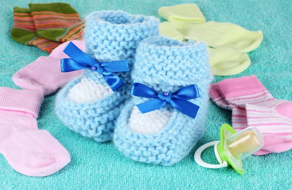 Botines de bebé azules, calcetines y chupete sobre fondo azul — Foto de Stock