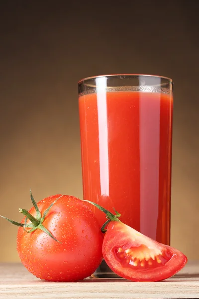 在玻璃和棕色表现力上的木桌上的番茄中的番茄汁 — 图库照片