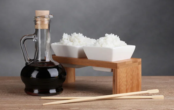 Bowls of cooked rice and soy sauce in jar on wooden table — Stock Photo, Image