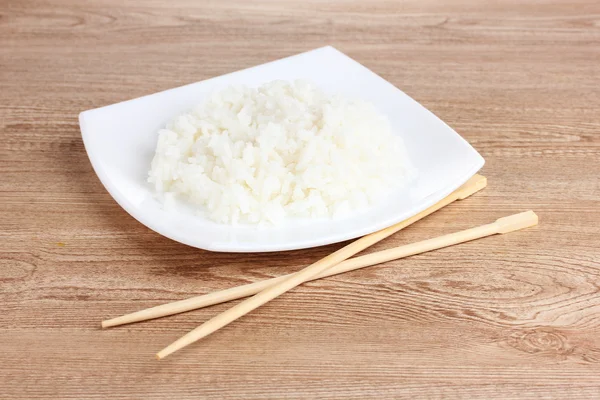 Белая миска с вареным рисом и палочками для еды — стоковое фото