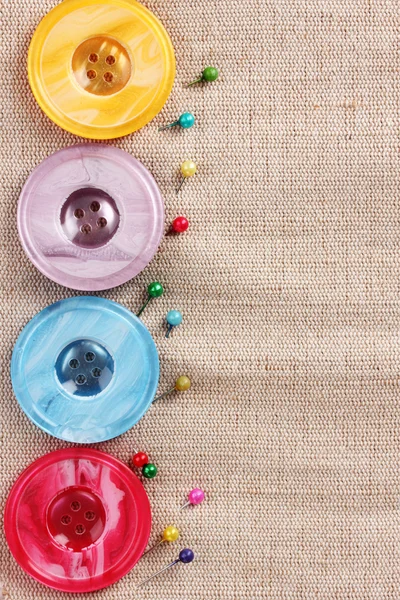 Bright sewing buttons and pins on gray fabric — Stock Photo, Image