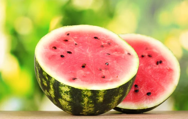 Reife süße Wassermelone auf Holztisch auf grünem Hintergrund — Stockfoto