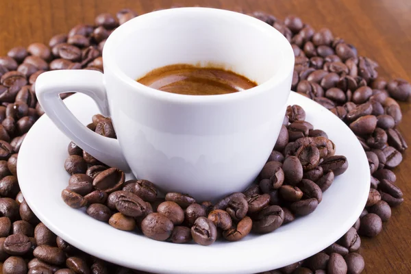 Espressokaffe omgiven med kaffebönor — Stockfoto