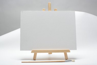 Blank canvas on easel isolate on white background clipart