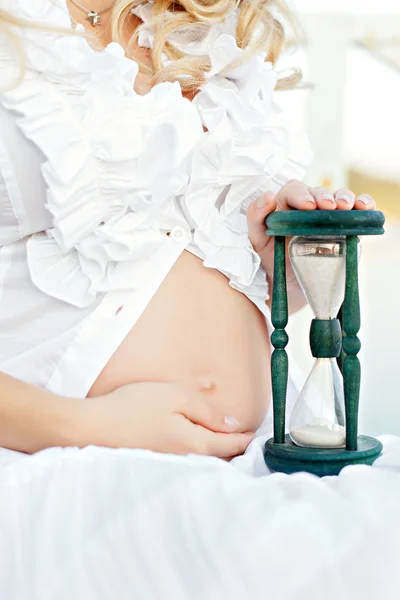 美しい妊娠中の腹と砂時計 — ストック写真