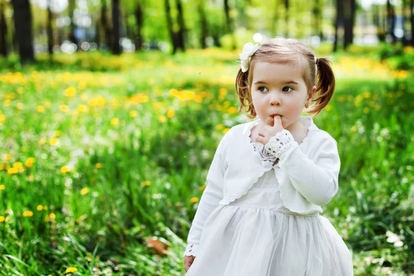 Cute girl in the park with dandelions — Stock Photo, Image