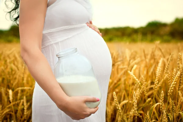 Cute belly pregnant girl with a jar of milk in the — Stock Photo, Image