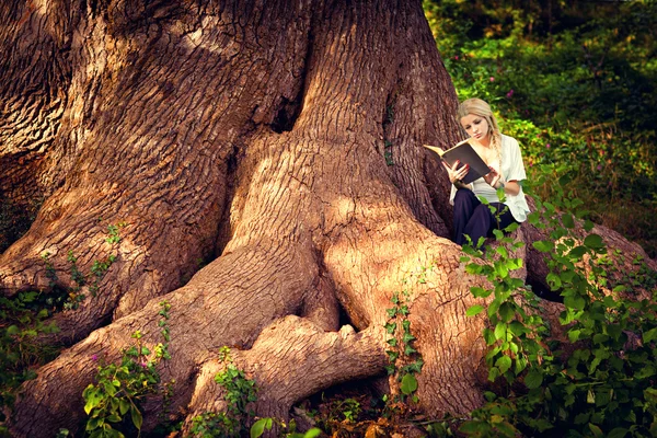 Cute dziewczyna w ciąży, czytanie na korzenie starych drzew — Zdjęcie stockowe
