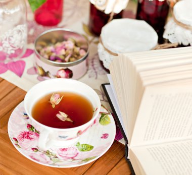 Cup of tea and a book on the table clipart