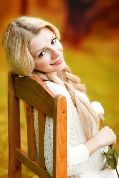 Ładny dziewczyna siedzi na krześle z różą — Zdjęcie stockowe