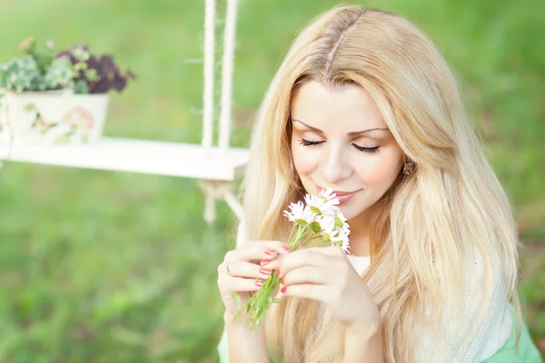Cute blonde with a bouquet of daisies and swing — Stock Photo, Image