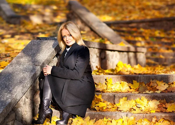 Linda rubia se sienta en las escaleras en hojas de otoño —  Fotos de Stock