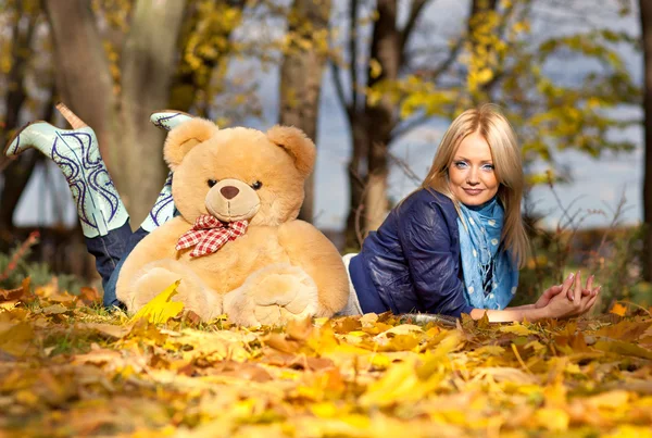 Hermosa chica en el otoño las hojas con un oso de peluche —  Fotos de Stock