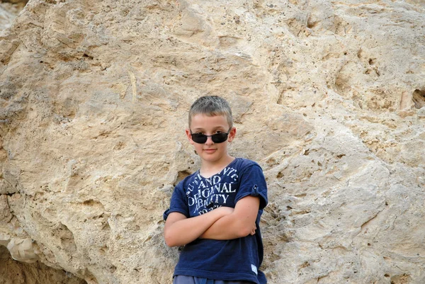 Child boy on the background of the stone cliffs poses — Stock Photo, Image