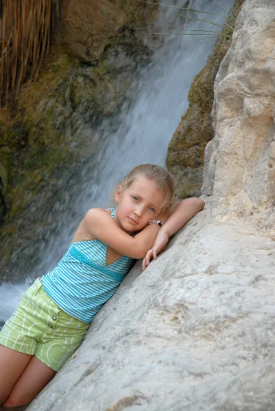 Anak gadis di latar belakang air terjun pose — Stok Foto