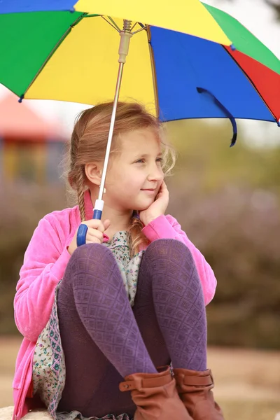 Porträt eines kleinen Mädchens mit einem farbigen Regenschirm — Stockfoto