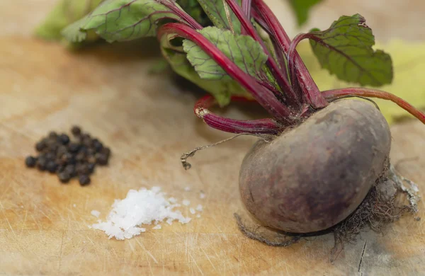 One beetroot on chopping board with salt & pepper. — Stock Photo, Image
